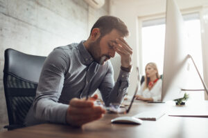 Businessman stressed sitting at the desk with head in hands