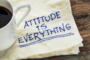 "Attitude is Everything" written on a napkin next to a coffee cup